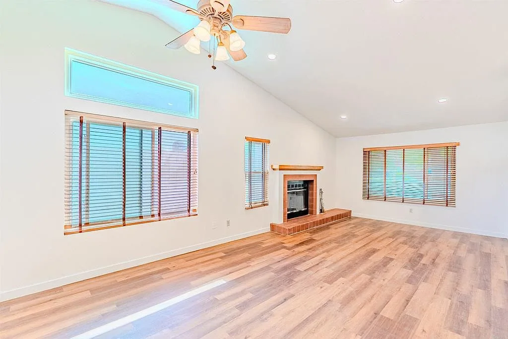 Living room with the red brick fireplace and wood blinds