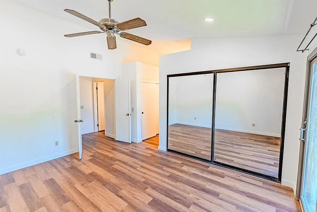 Bedroom with mirrored closet doors and vaulted ceiling