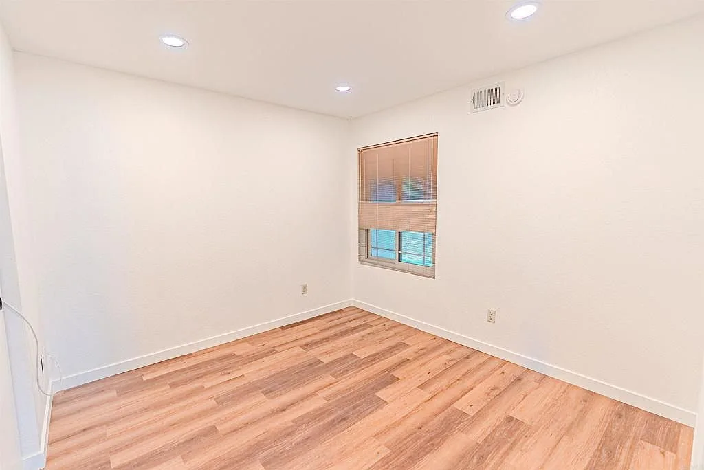 Secondary bedroom with wood blinds and recessed lighting