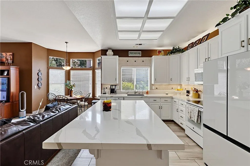 Kitchen at 1755 E Tuolumne Rd with a white quartz island flowing into the family room with warm-toned walls