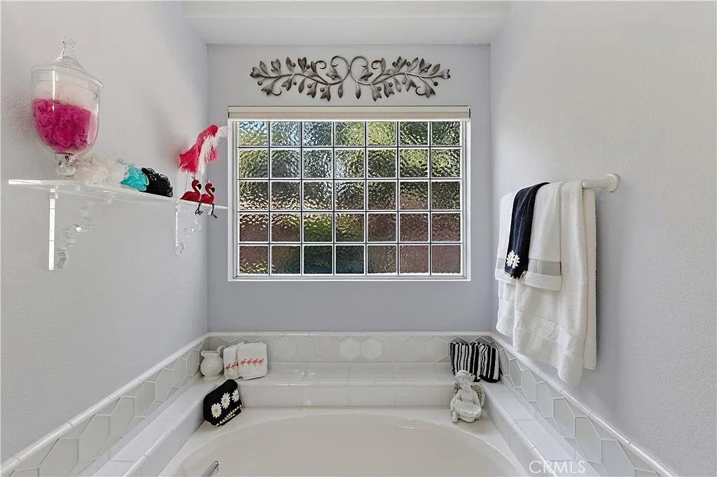 Built-in soaking tub at 1755 E Tuolumne Rd with a glass block window and white tiled surround