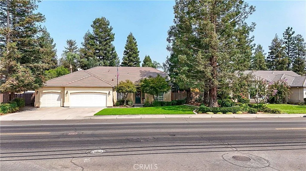 Street view of the single-story home at 1755 E Tuolumne Rd with an attached garage, tall redwood trees and a manicured lawn