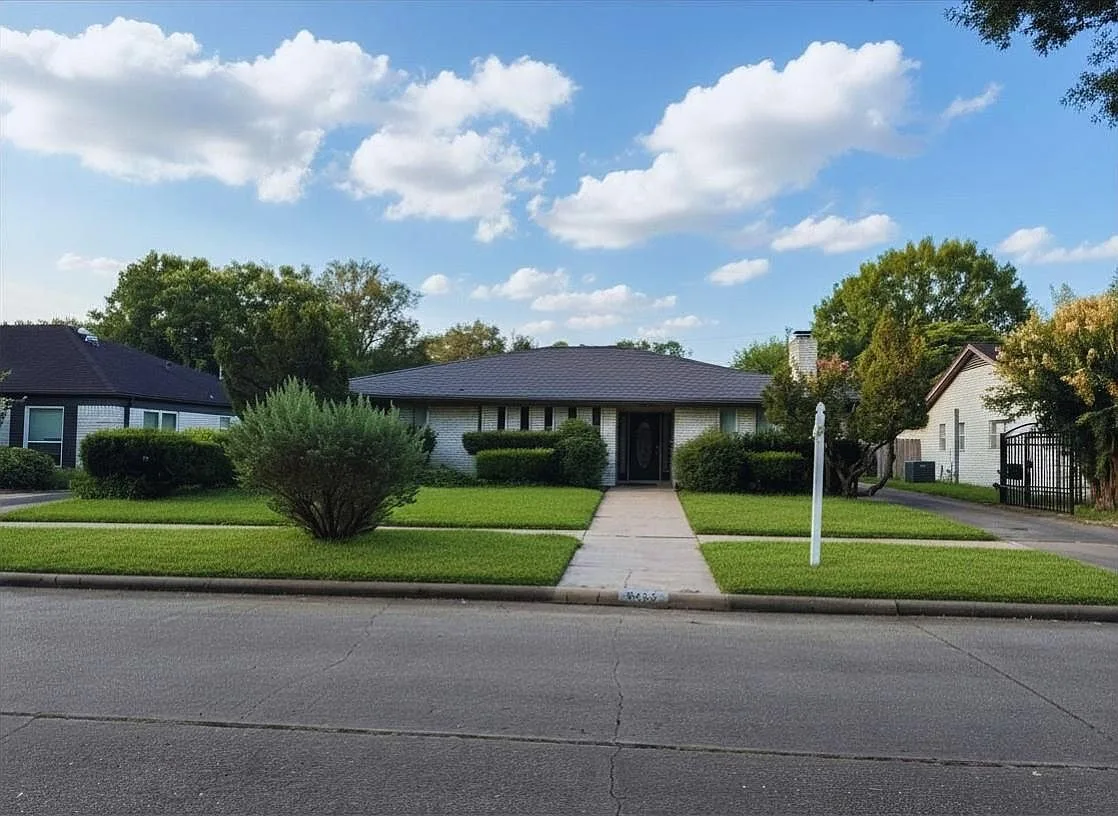 Front exterior of 6203 Wigton Dr, a mid-century brick ranch with a manicured lawn on a tree-lined street