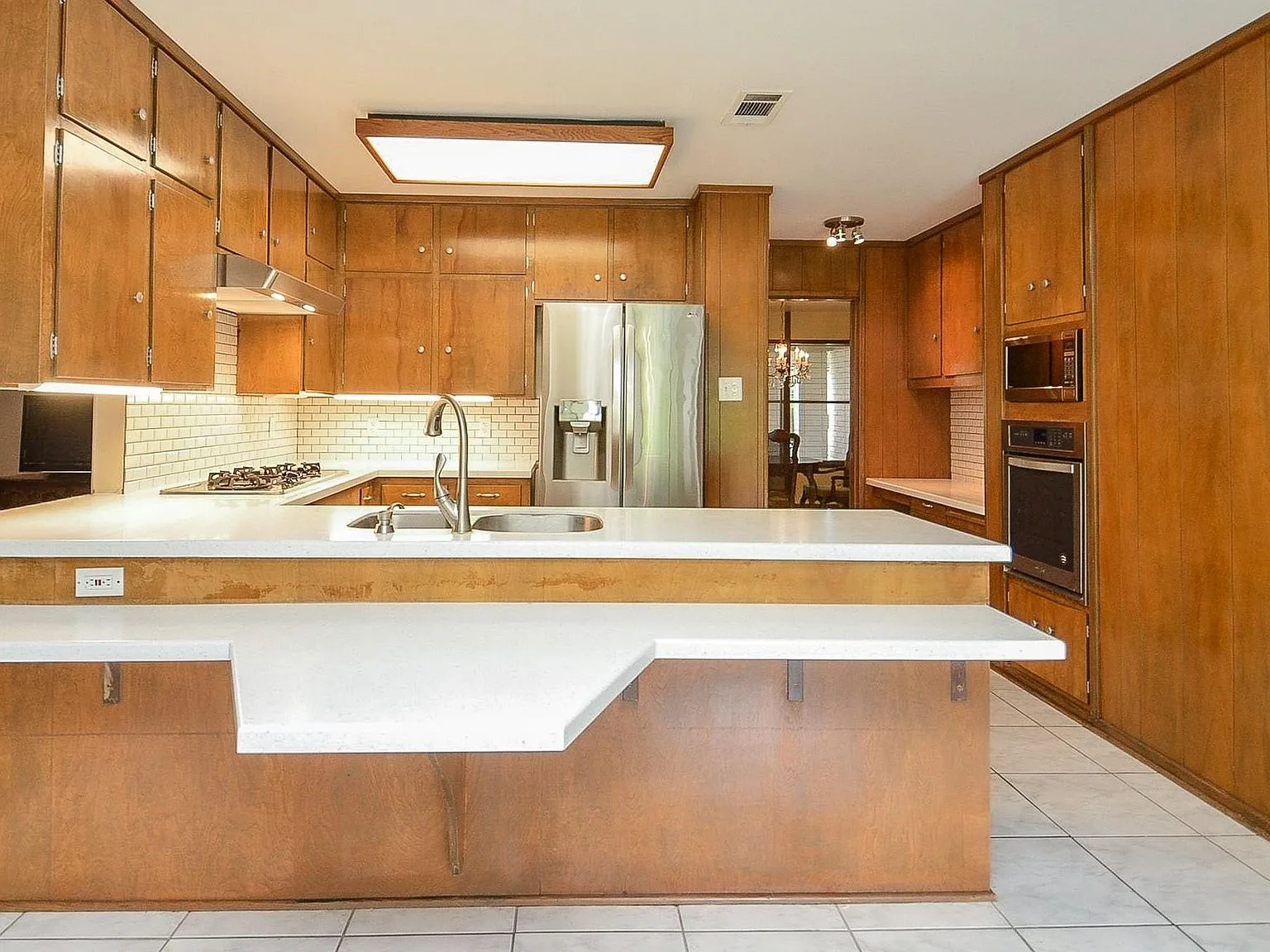 Mid-century kitchen with wood-paneled cabinetry and white countertops