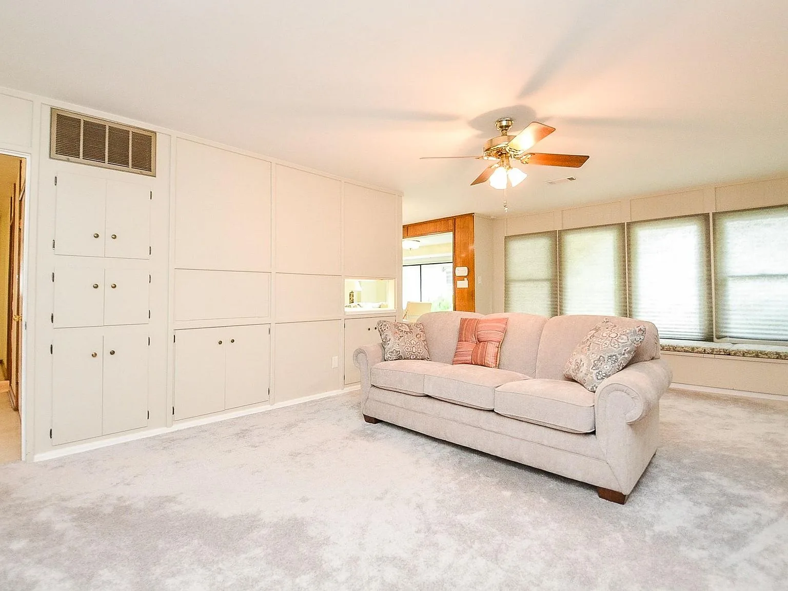 Living room with built-in cabinetry, wall-to-wall carpet and large windows