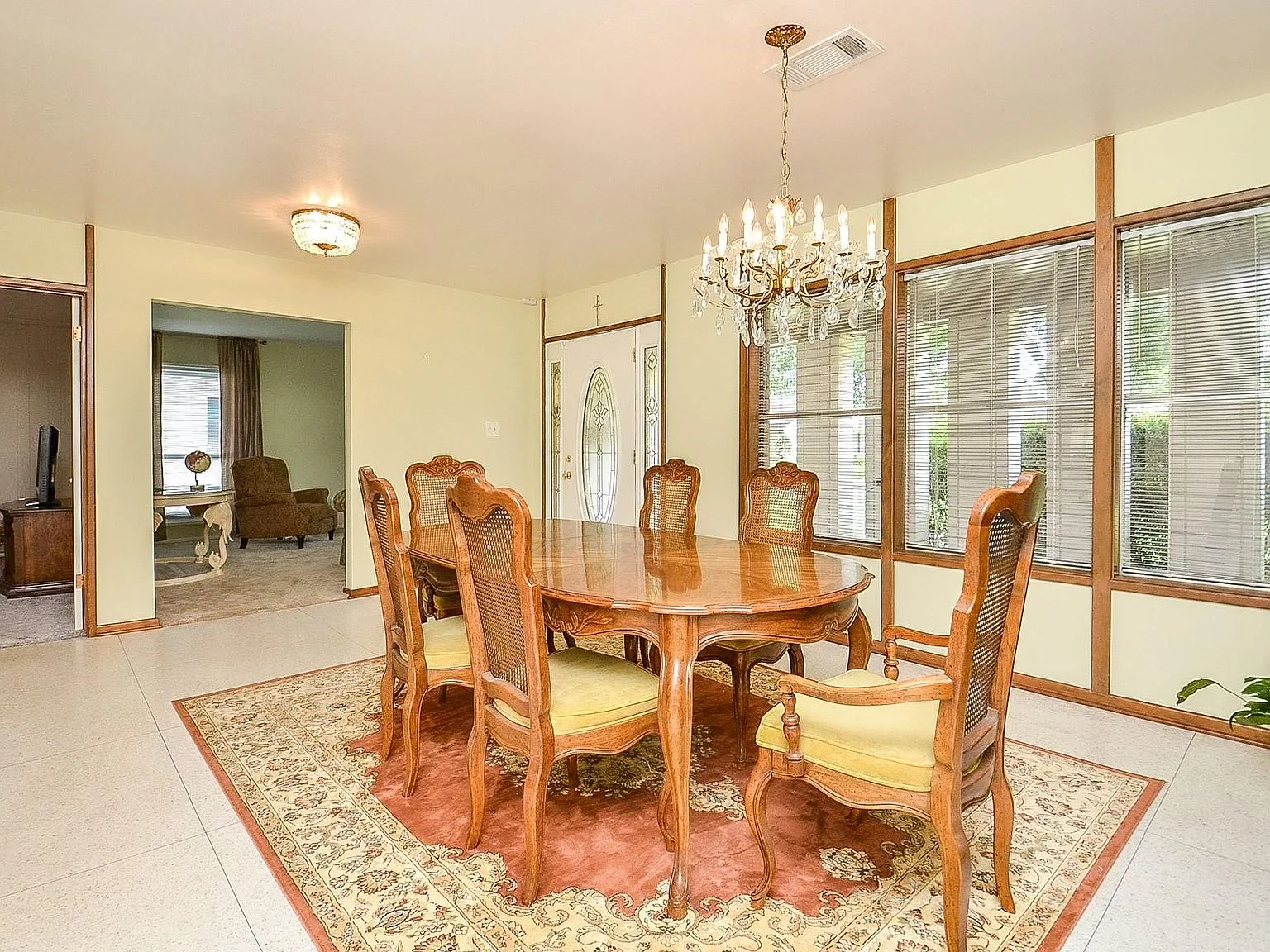 Dining room with light yellow walls and wood trim, opening into the living area