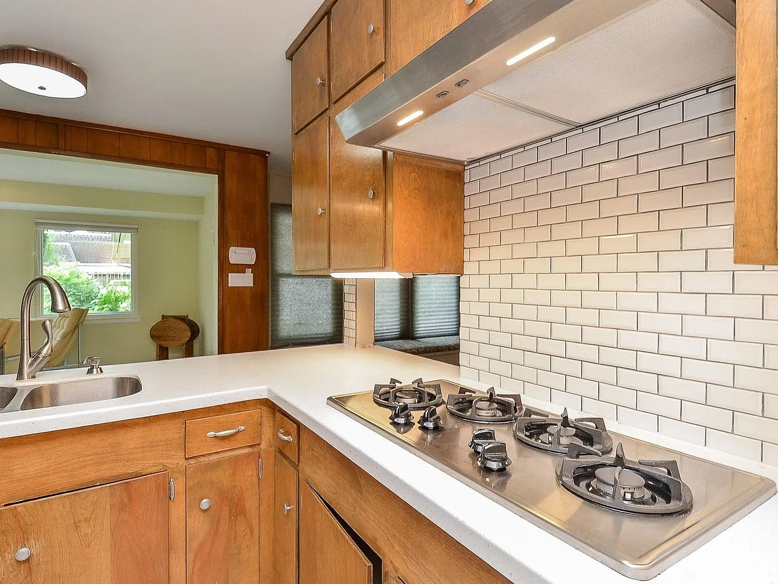 Kitchen detail with original wood cabinets, white countertops and subway tile backsplash