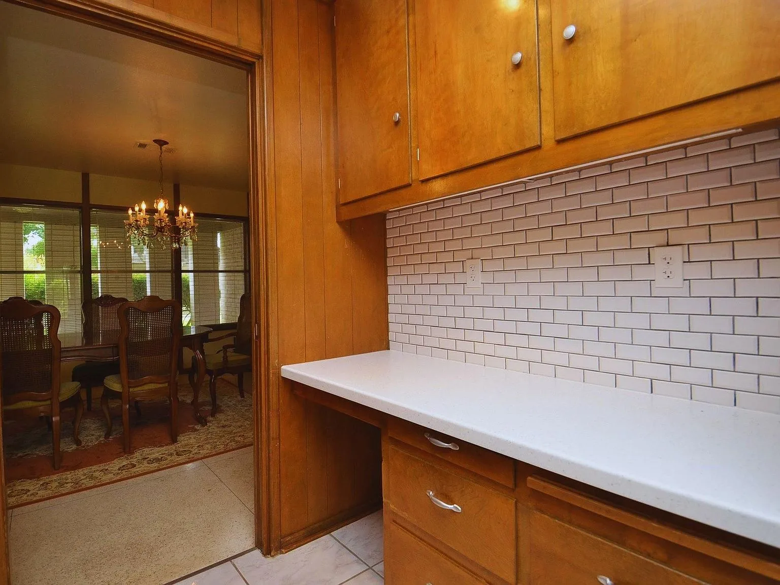 Butler's pantry with natural wood cabinetry and white tile flooring