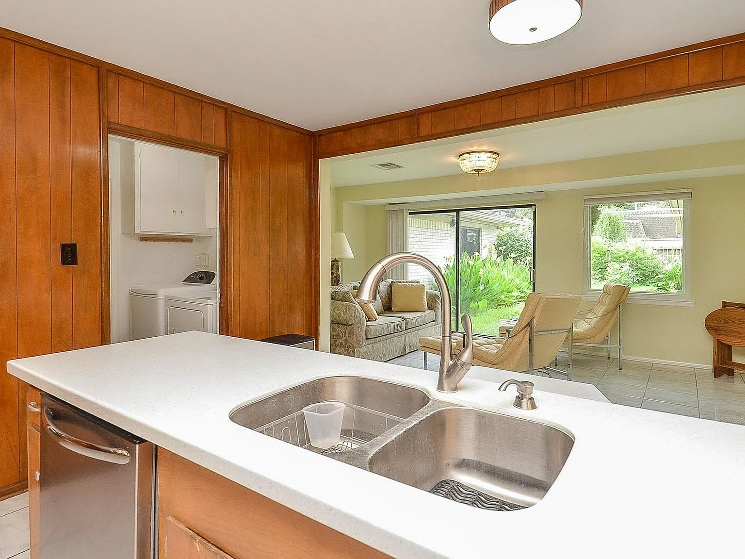 Kitchen with wood paneling and white countertops, view toward the living room
