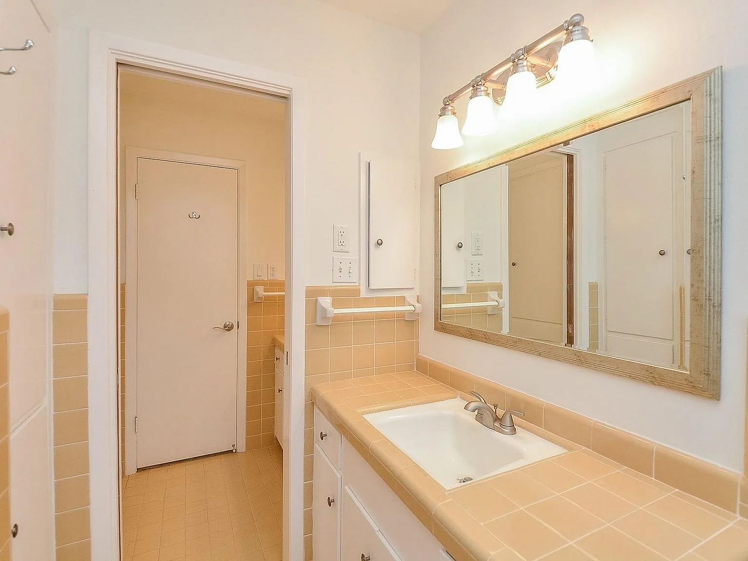 Bathroom vanity with beige tile countertop and white cabinetry