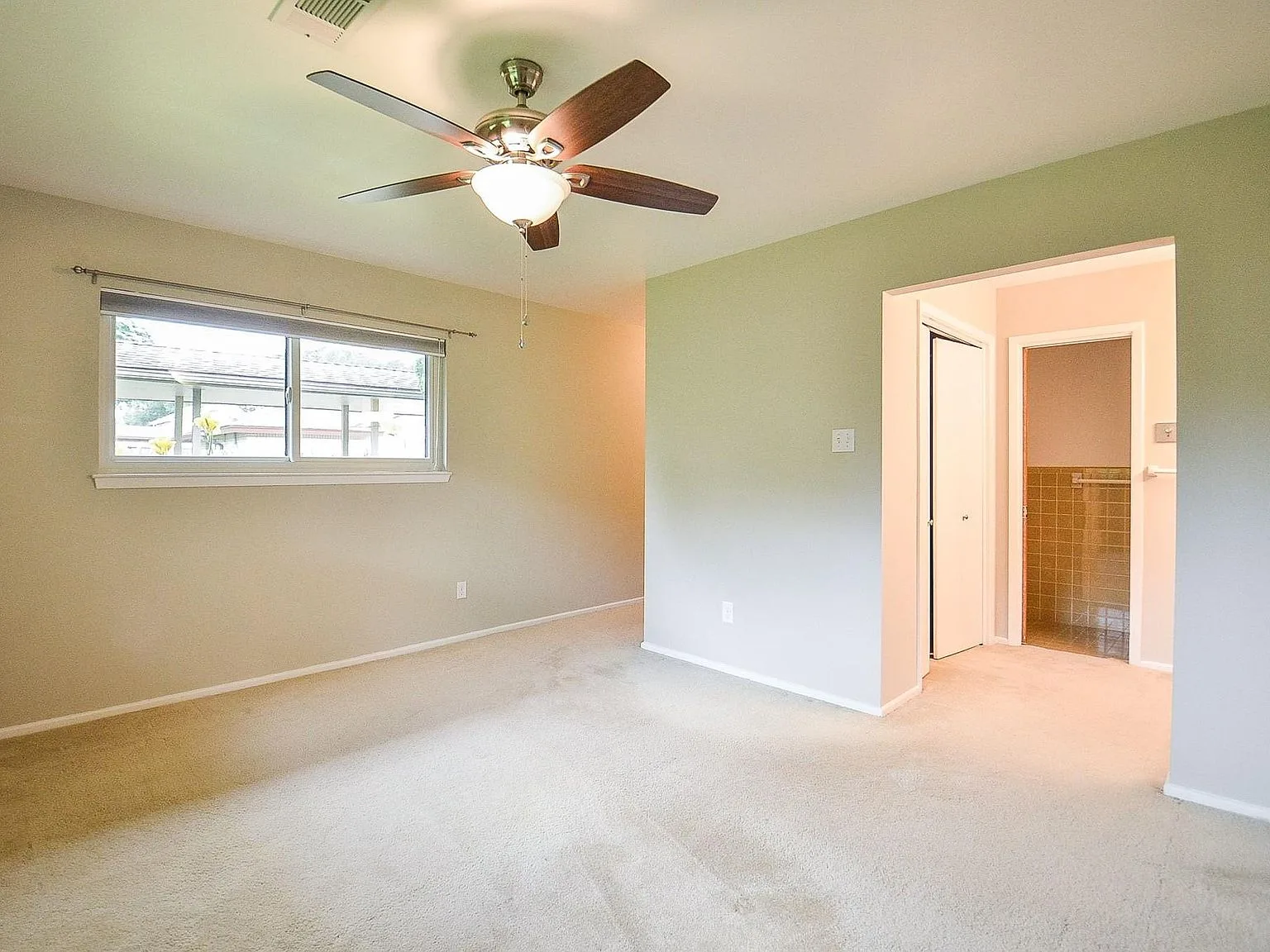 Primary bedroom with carpeted floors and a view toward the ensuite bath