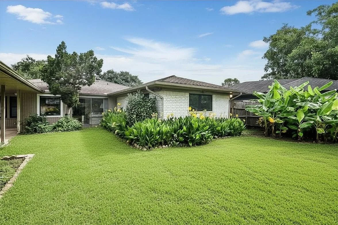 Spacious backyard view of the home with lawn and mature landscaping
