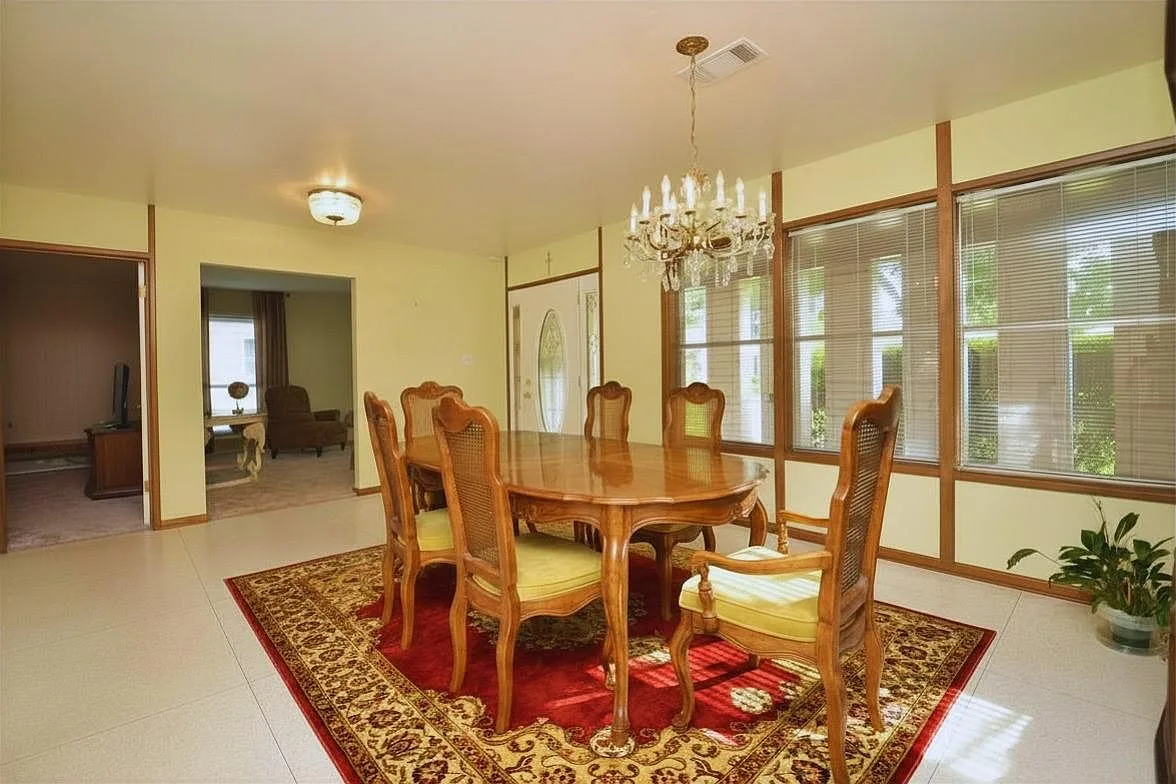 Formal dining room with an oval table, cane-back chairs and crystal chandelier
