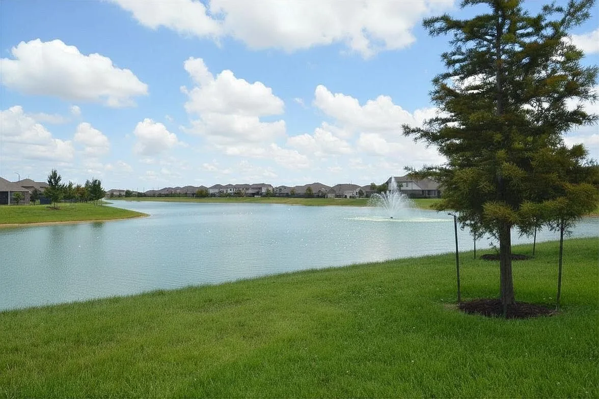 Community lake with an active fountain seen from the backyard