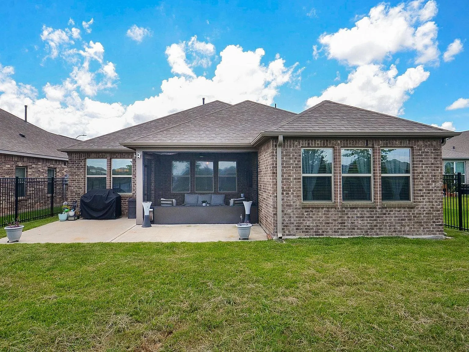 Rear elevation of the home with the large covered screened patio and brick siding