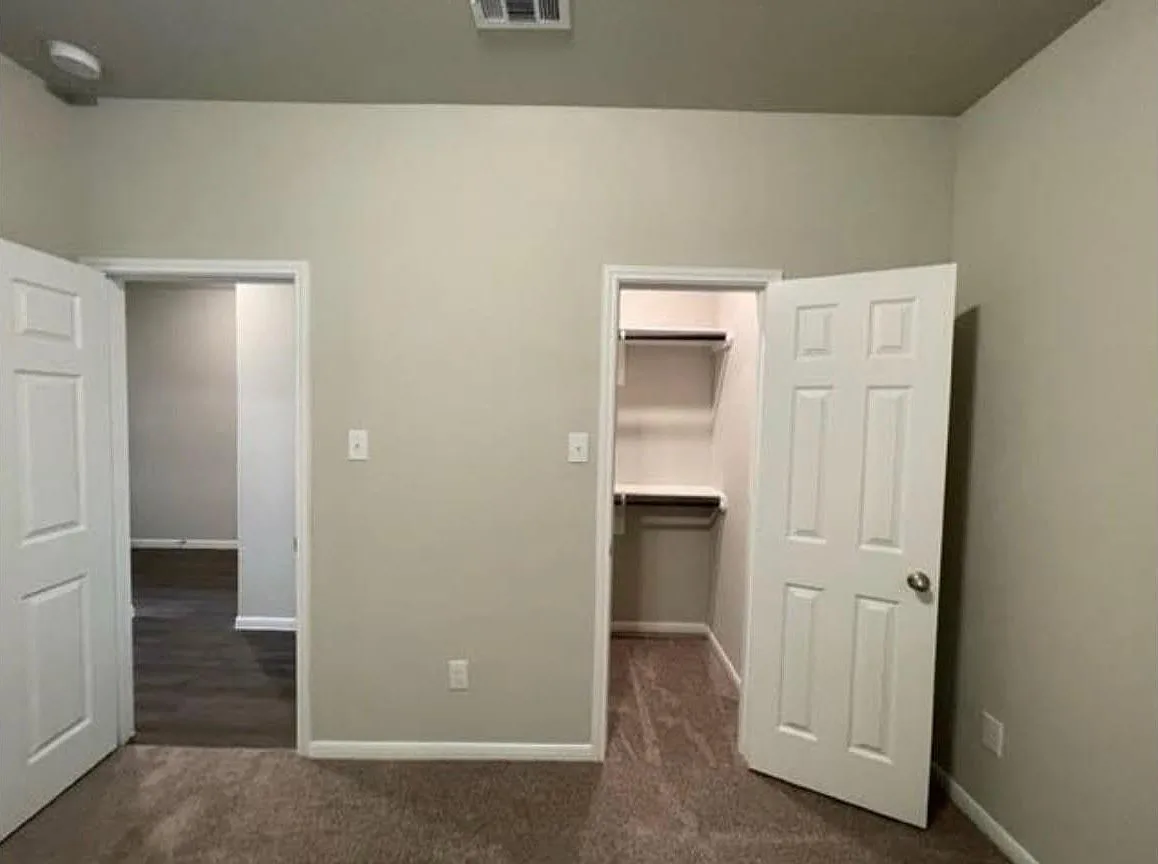 Secondary bedroom viewed toward its hallway and reach-in closet