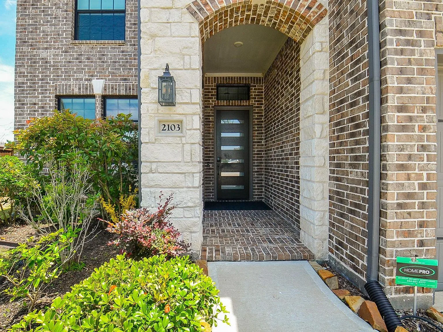 Covered arched front entry with modern multi-panel glass door
