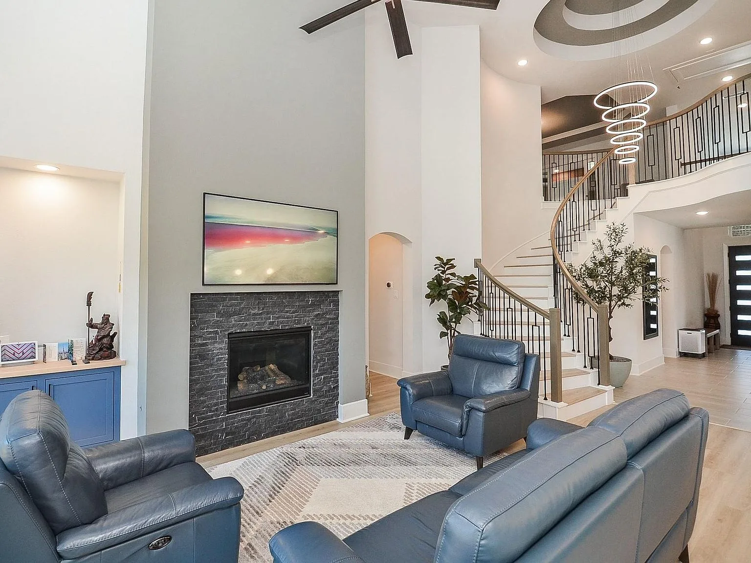 Living room with stone-faced fireplace and curved staircase