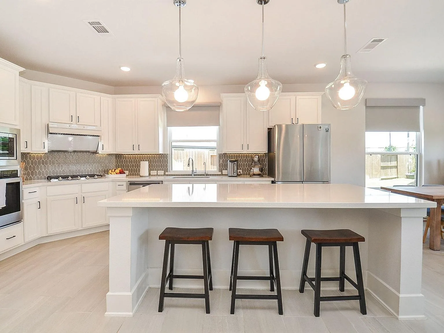 Chef-inspired kitchen with large white island and patterned backsplash