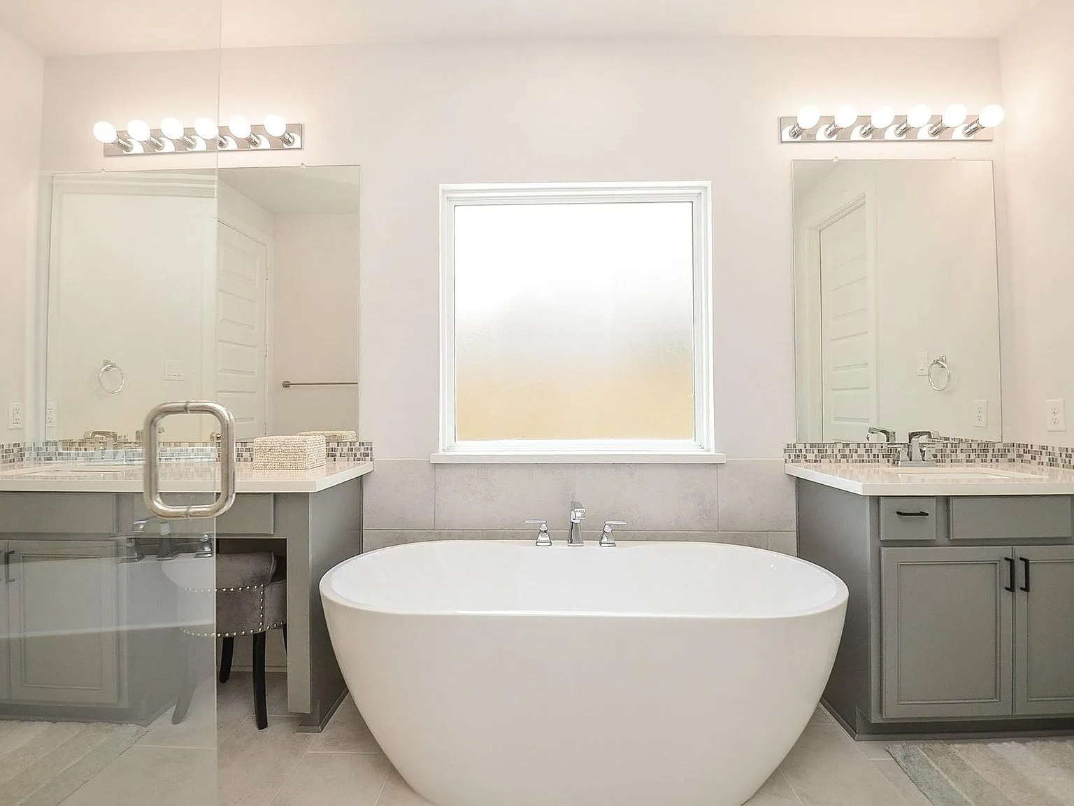 Primary bath with freestanding soaking tub and gray cabinetry