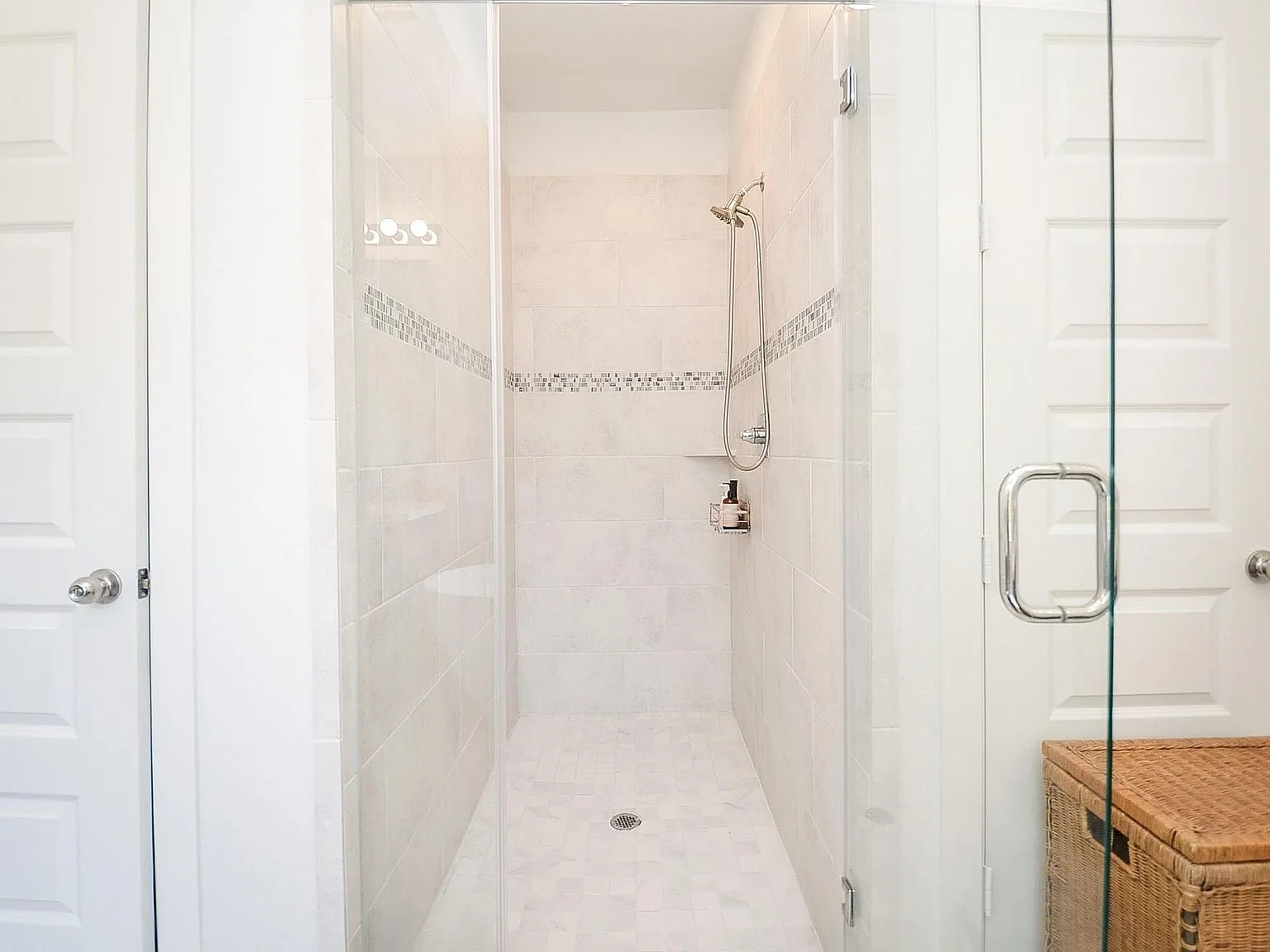 Glass-enclosed walk-in shower with mosaic accent tile