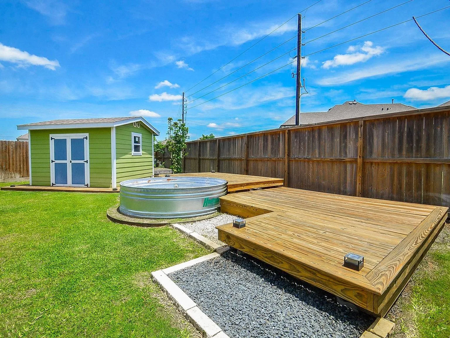Backyard with circular stock tank pool, wood decking, and fruit trees