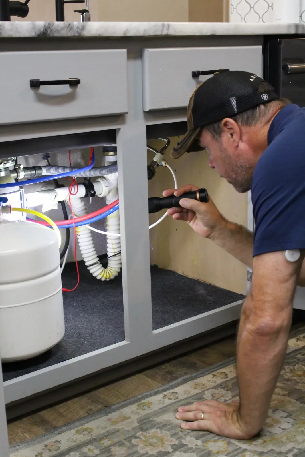 Under-sink plumbing inspected with a flashlight during a Rodeo home inspection in San Antonio