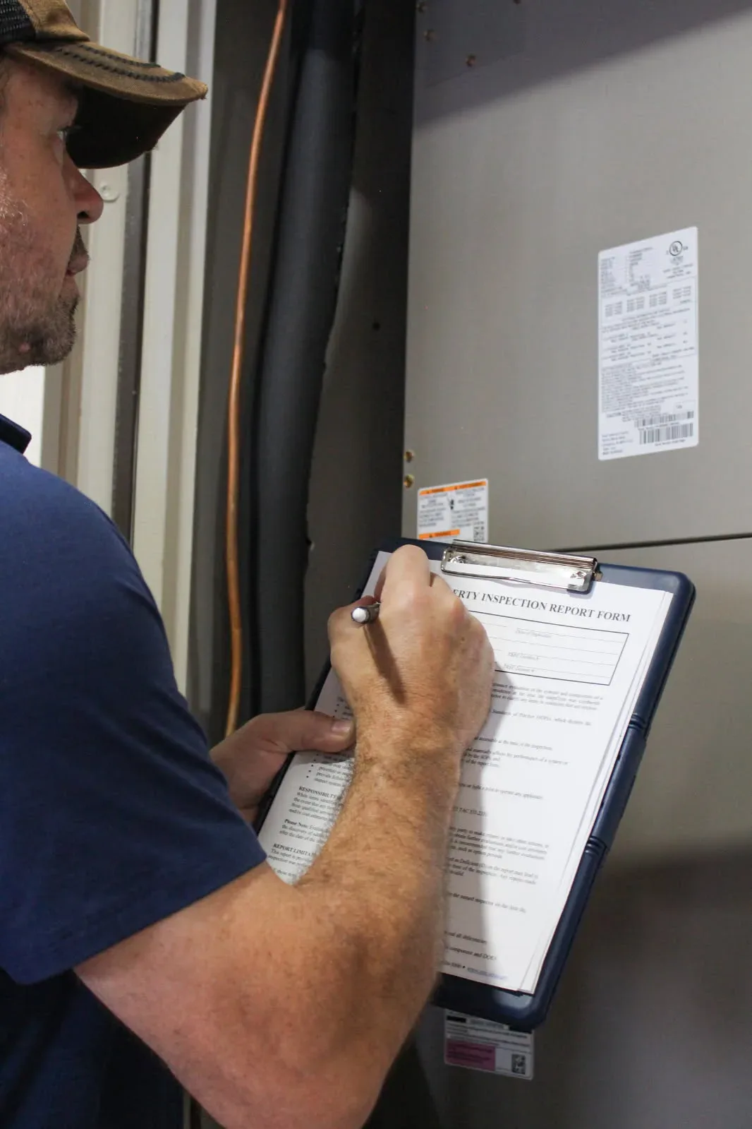 Christian Schmeis writing findings on a Property Inspection Report Form during a Rodeo home inspection