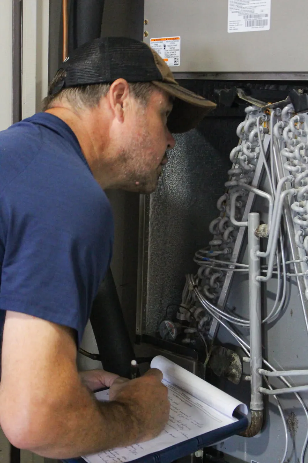 A Rodeo Home Inspections LLC inspector checking an HVAC unit, its coils, and refrigerant lines