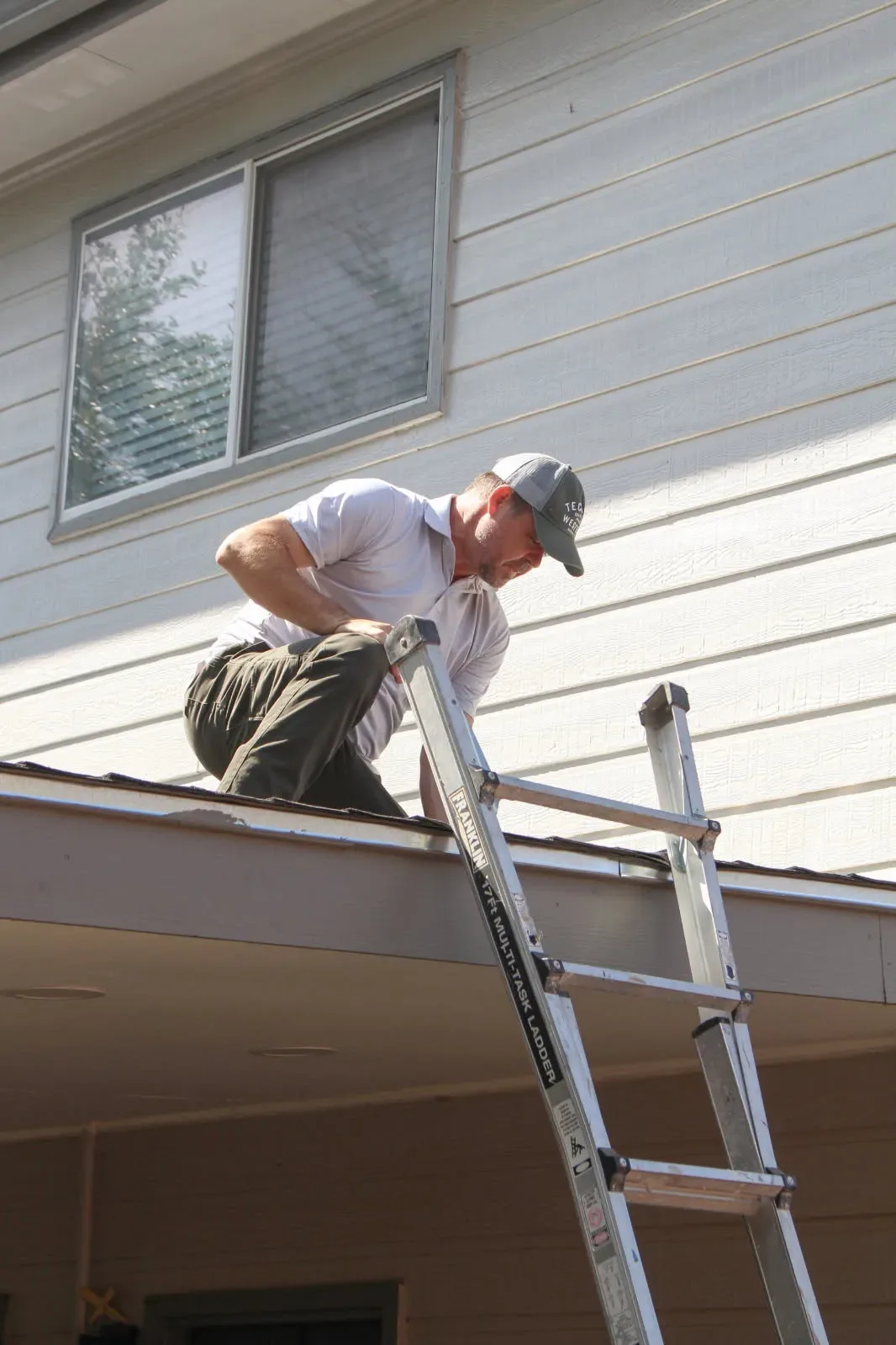A Rodeo Home Inspections LLC inspector working the roofline from a ladder during a roof and structural inspection
