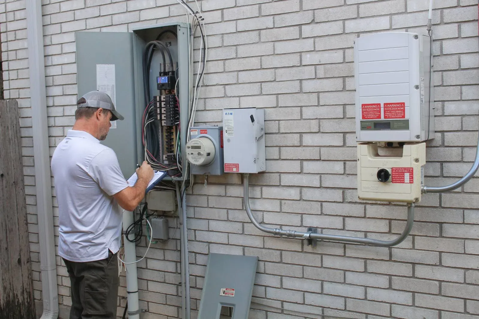 An inspector checking the electrical panel, meter, and service equipment during a new construction inspection