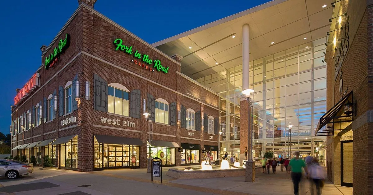 The Streets at Southpoint entrance with brick facade, shopping signage, and fountain walkway at dusk in South Durham