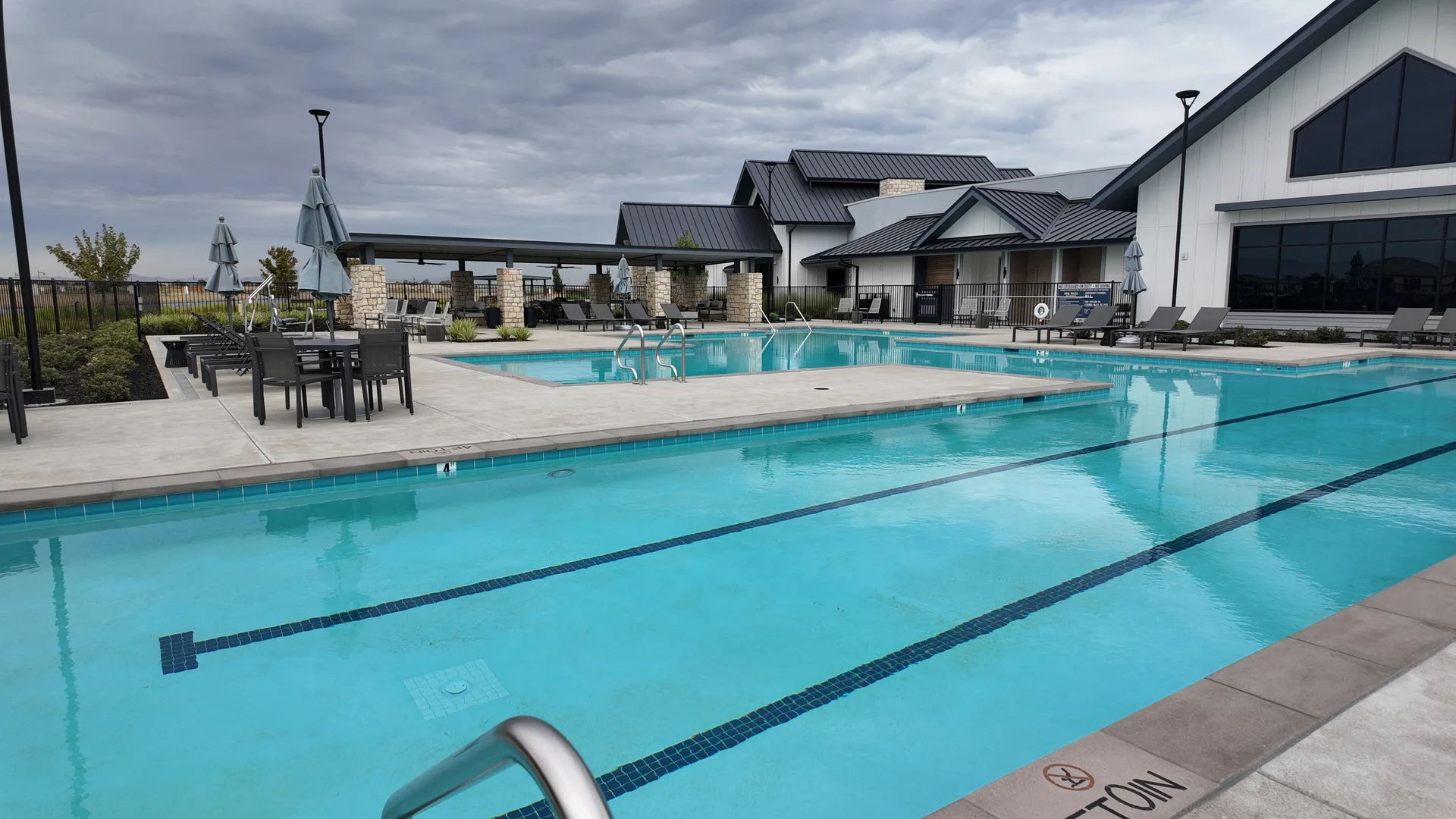 Resort-style outdoor pool with swim lanes at the Lakeview Club at Del Webb at River Islands in Lathrop, California, surrounded by loungers and umbrellas