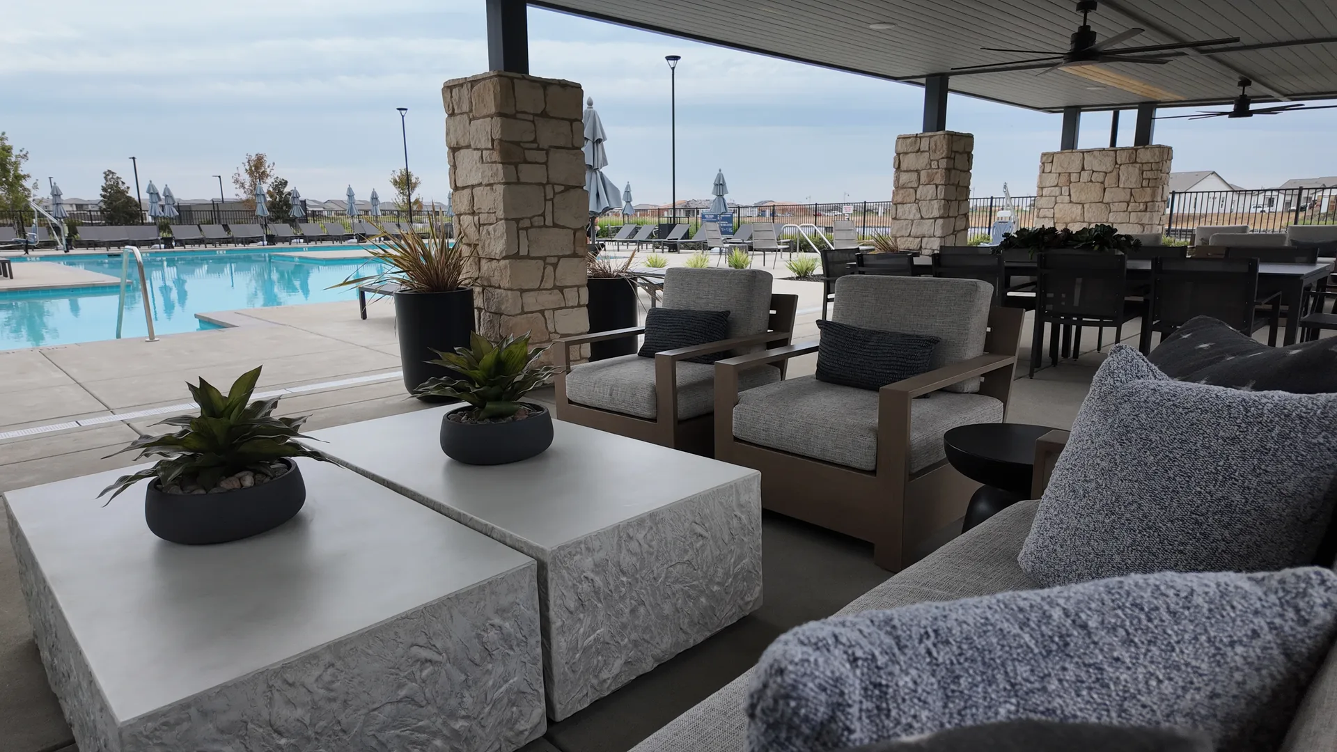 Pool lounge and spa at the Lakeview Club at Del Webb at River Islands in Lathrop, California, with chaise lounges, umbrellas and conversation seating beside the water