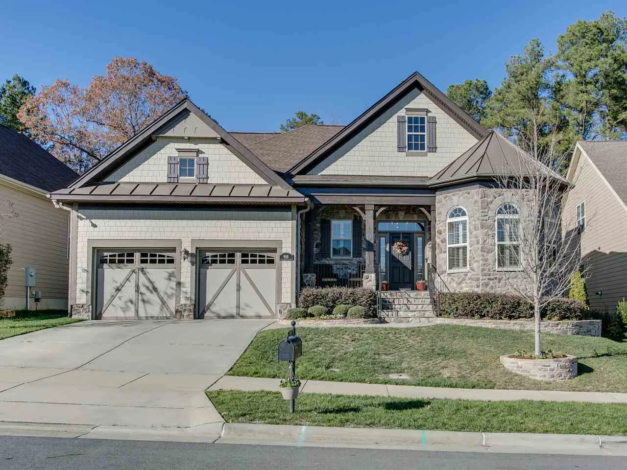 Craftsman-style suburban home with stone veneer, gabled roofline, and carriage-style garage doors in a Southpoint-area community