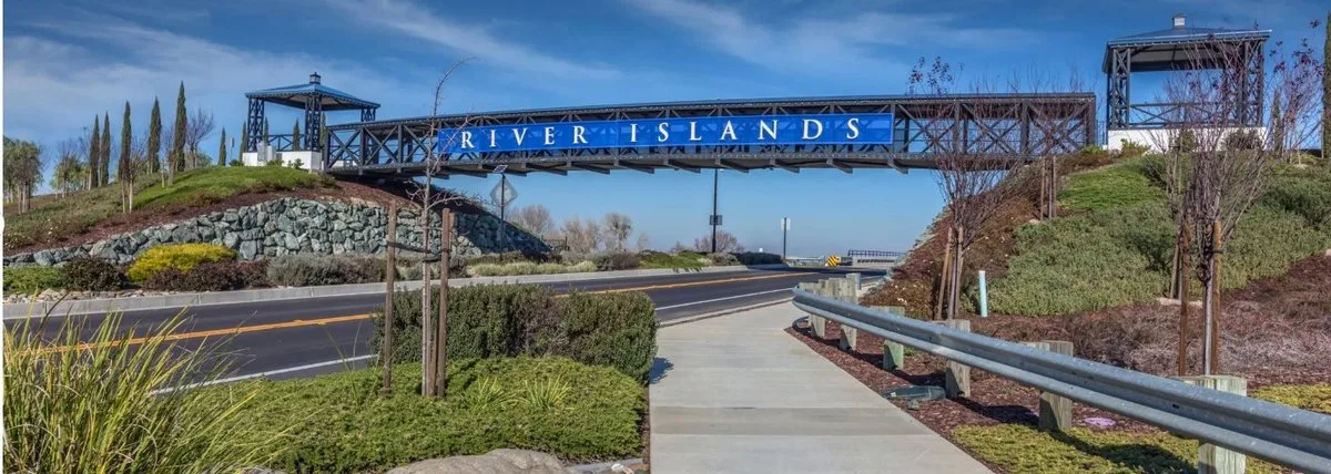 The entrance monument and gateway at River Islands in Lathrop, California, with a RIVER ISLANDS sign spanning the main roadway into the community