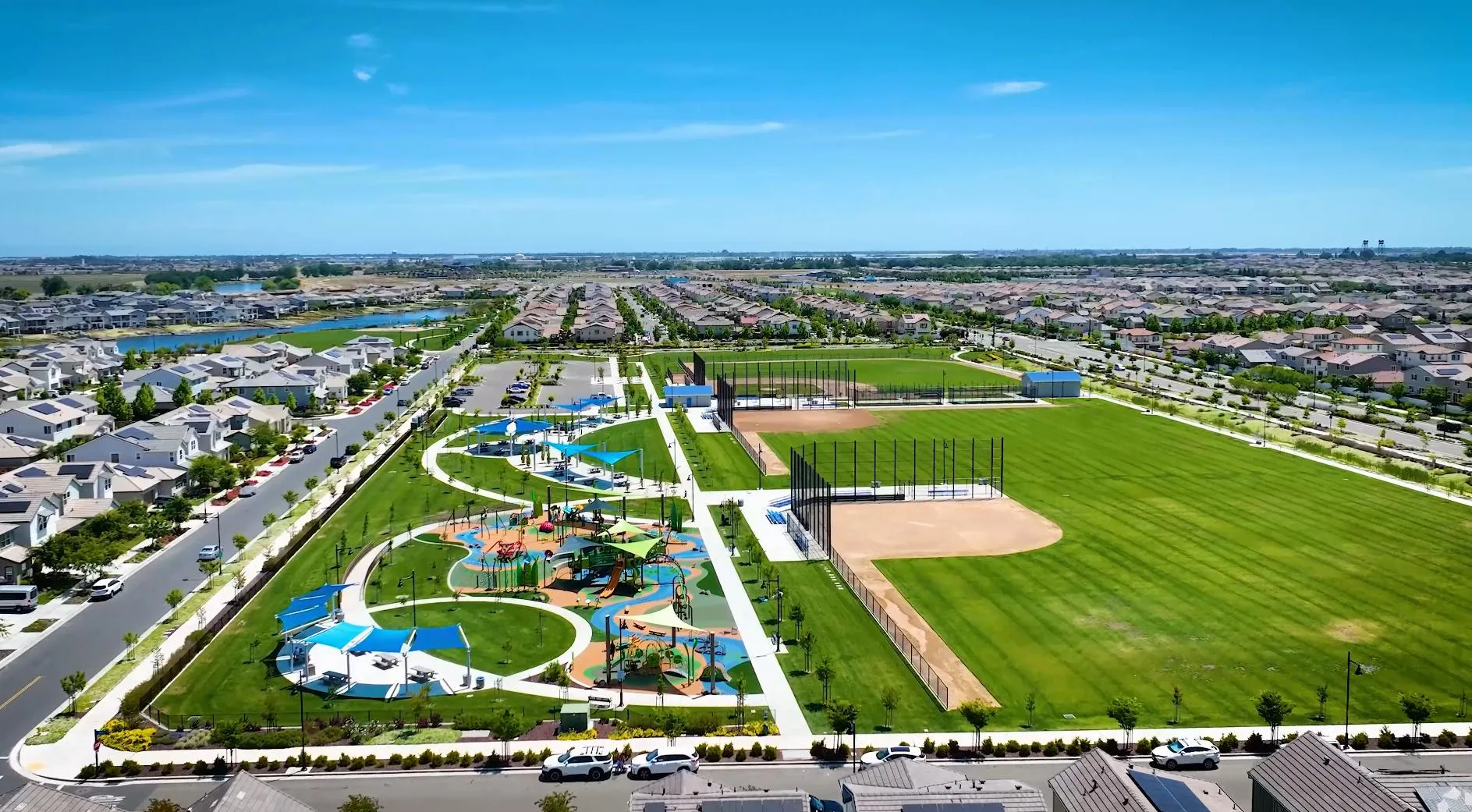 Aerial view of a community park at River Islands in Lathrop, California, with ballfields, a playground and blue shade sails
