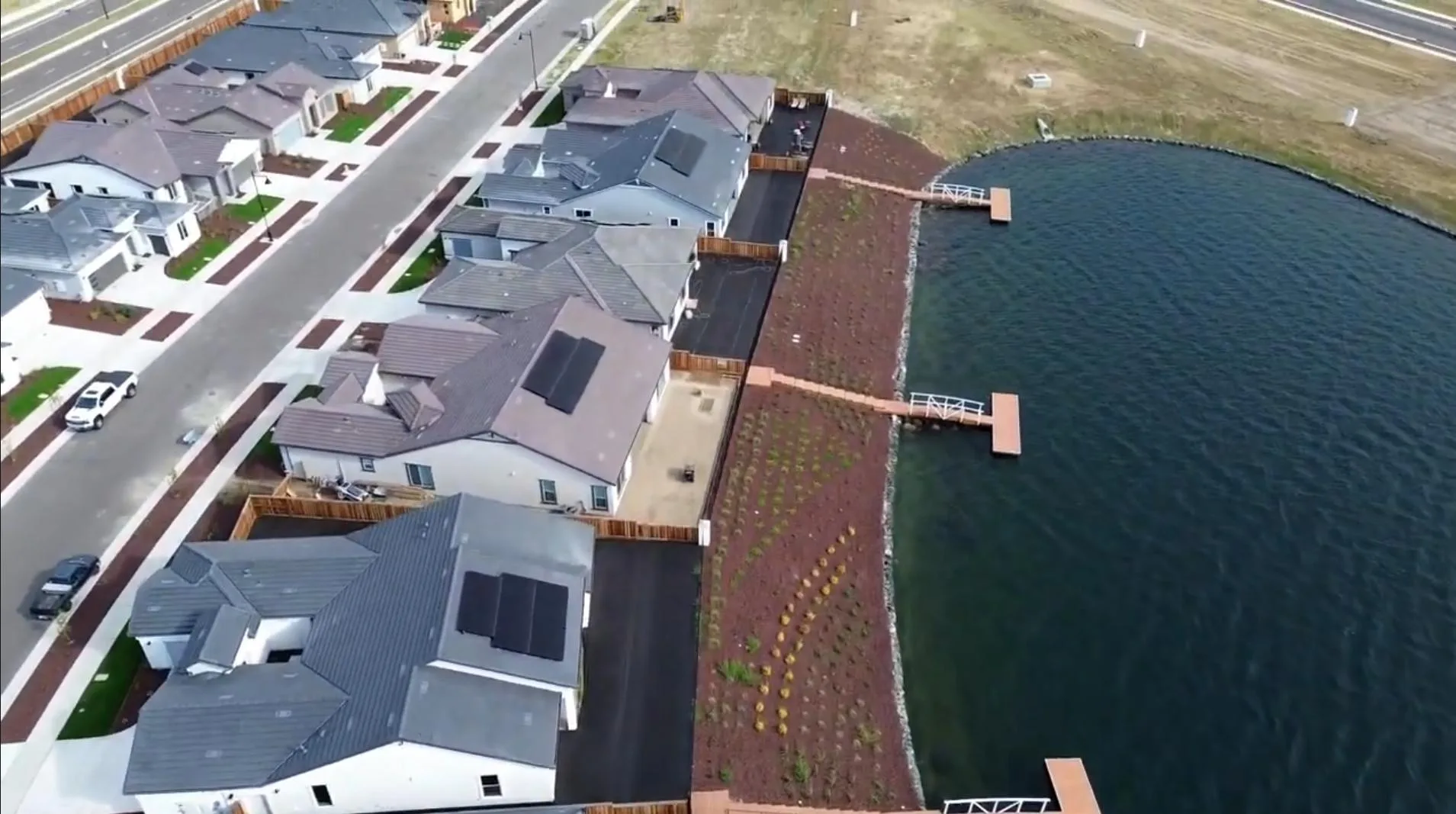Aerial view of lakefront homes with private docks along a lake at River Islands in Lathrop, California