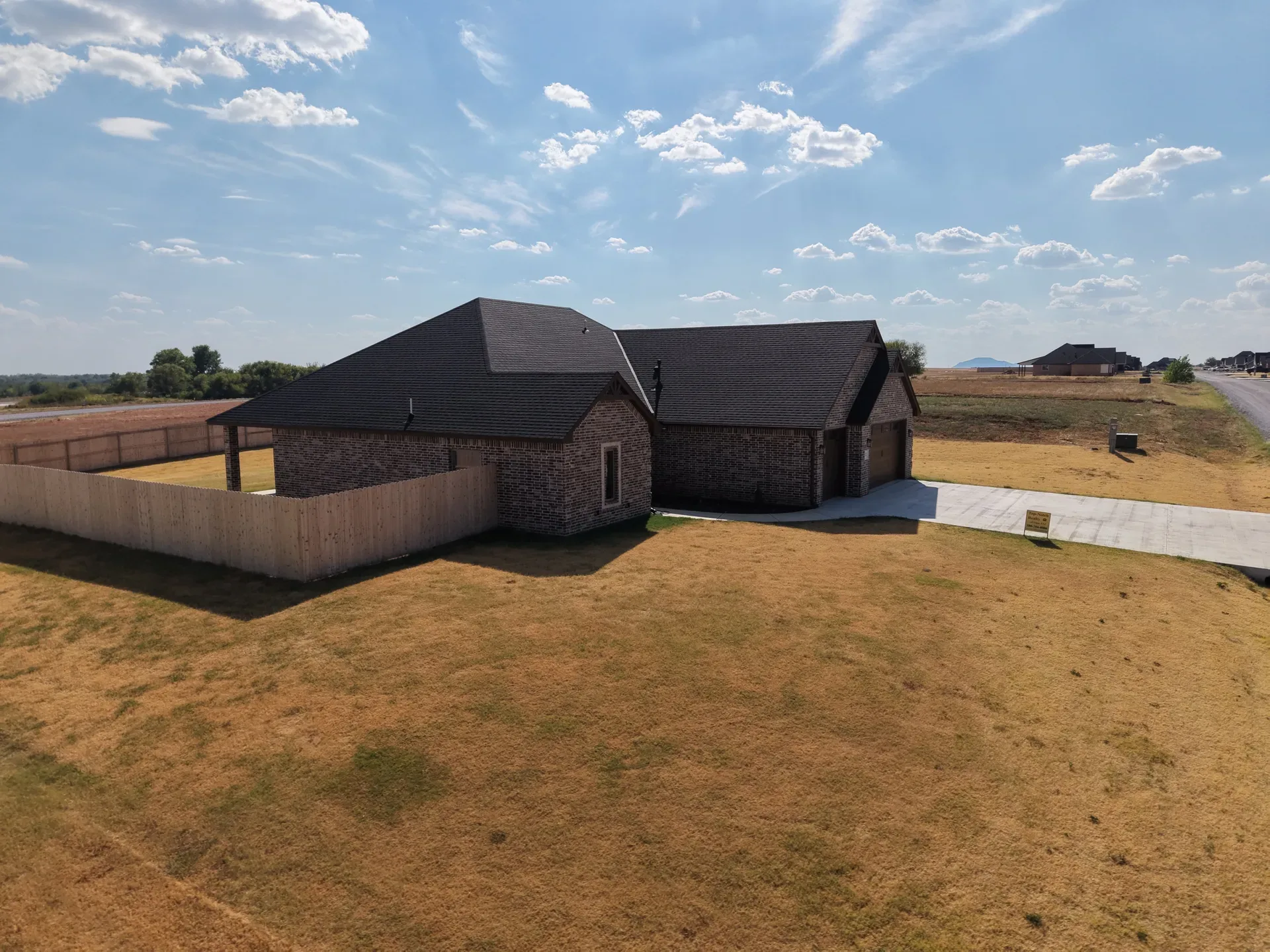 High-angle aerial of the ranch showing the side and rear yard behind the privacy fence