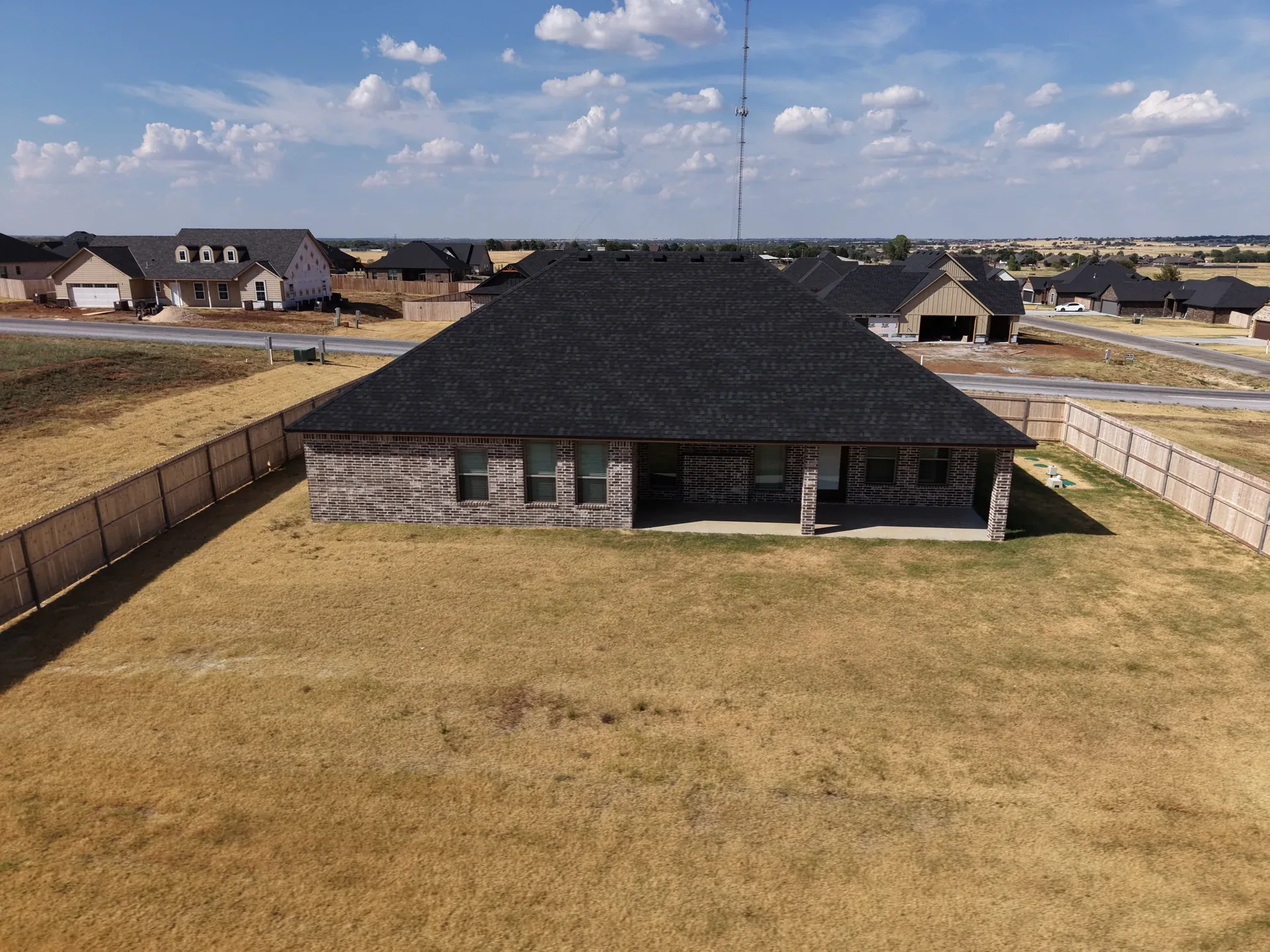 Aerial view of the large grassy backyard framed by wood privacy fencing