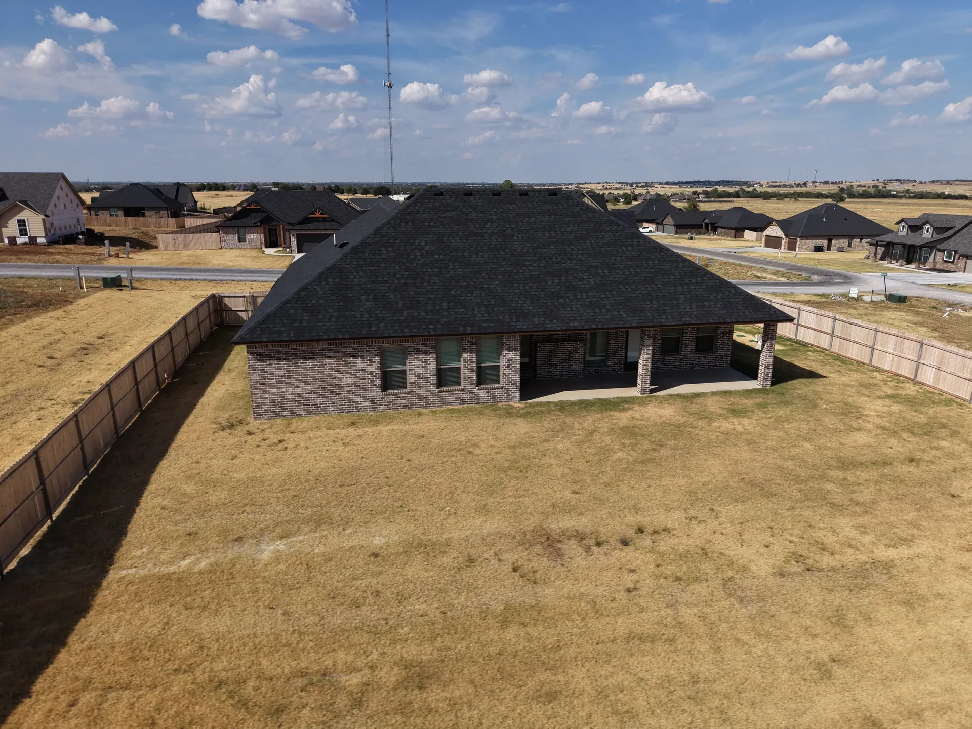 Aerial view of the rear exterior with open backyard and privacy fencing on both sides