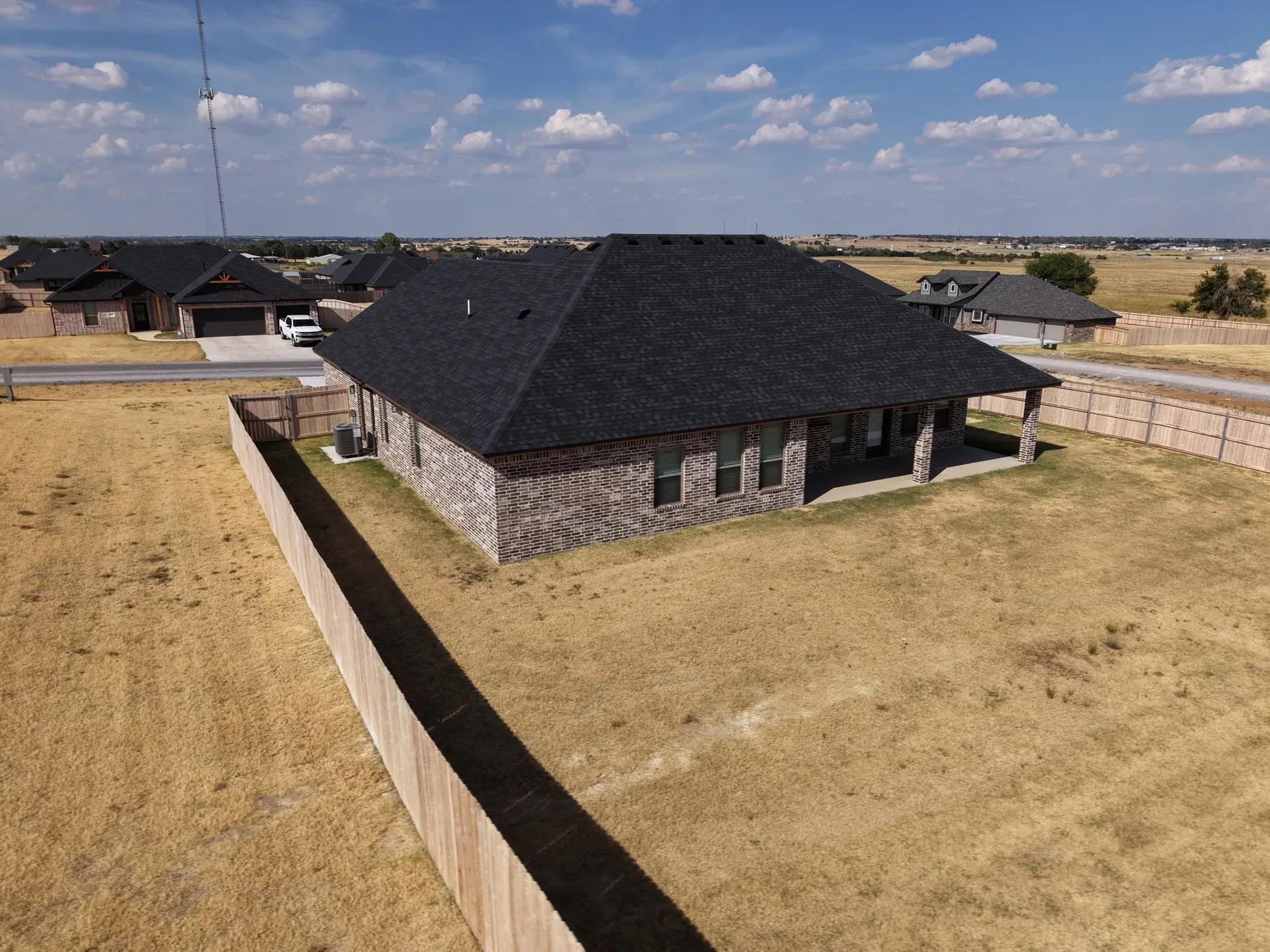 Drone aerial of the backyard, covered porch, and brick house exterior