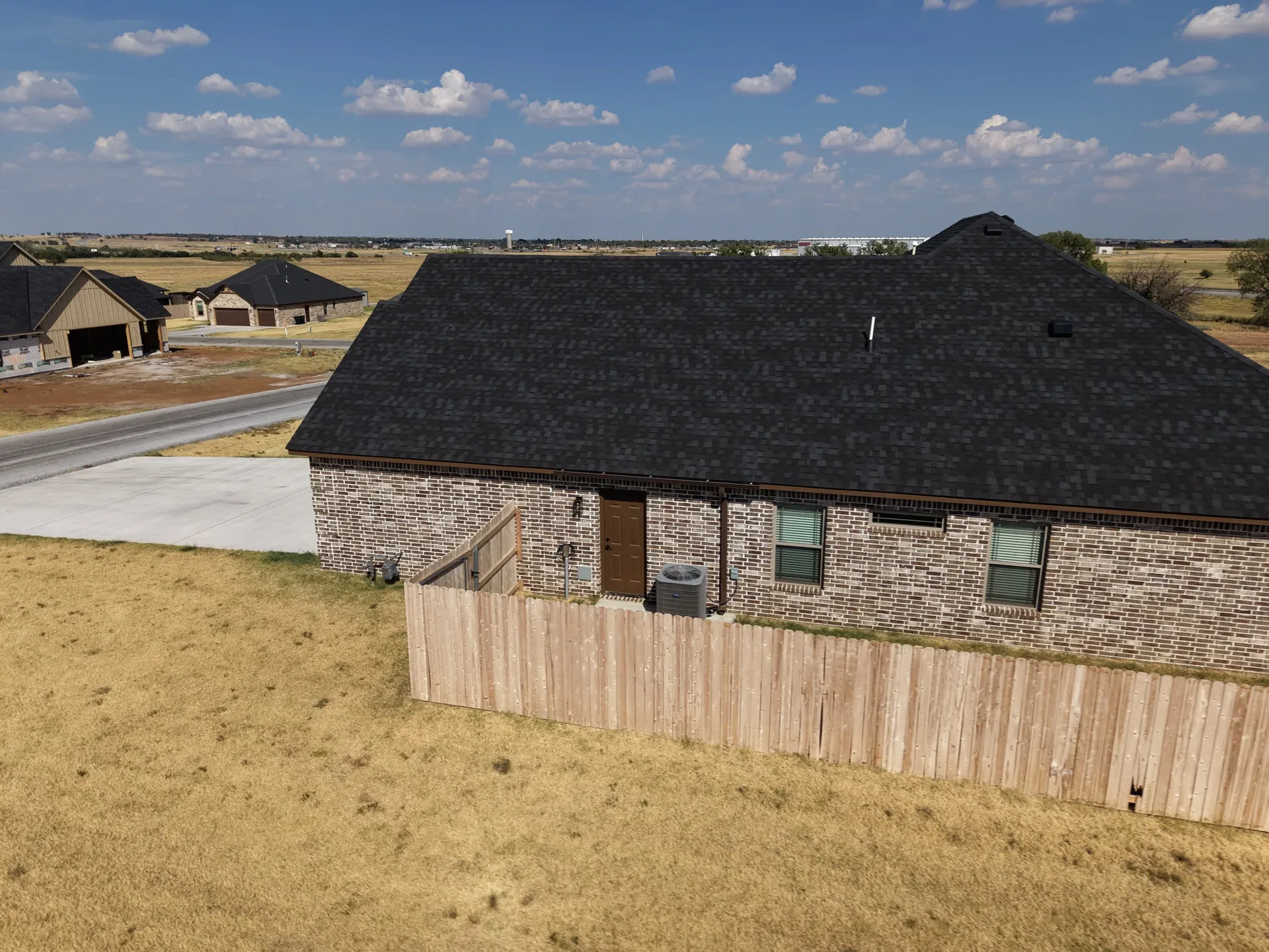 Top-down drone shot of the backyard, rear facade, and surrounding lot
