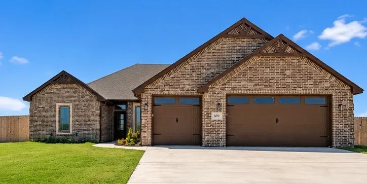 Front exterior of the single-story brick ranch at 5873 NE Minnow Ln with garage and gable trim