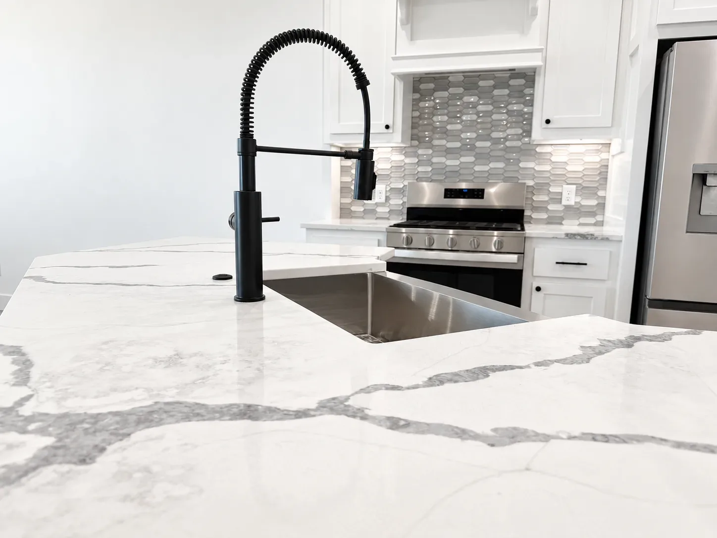Kitchen island with white quartz countertop, undermount sink, and black gooseneck faucet