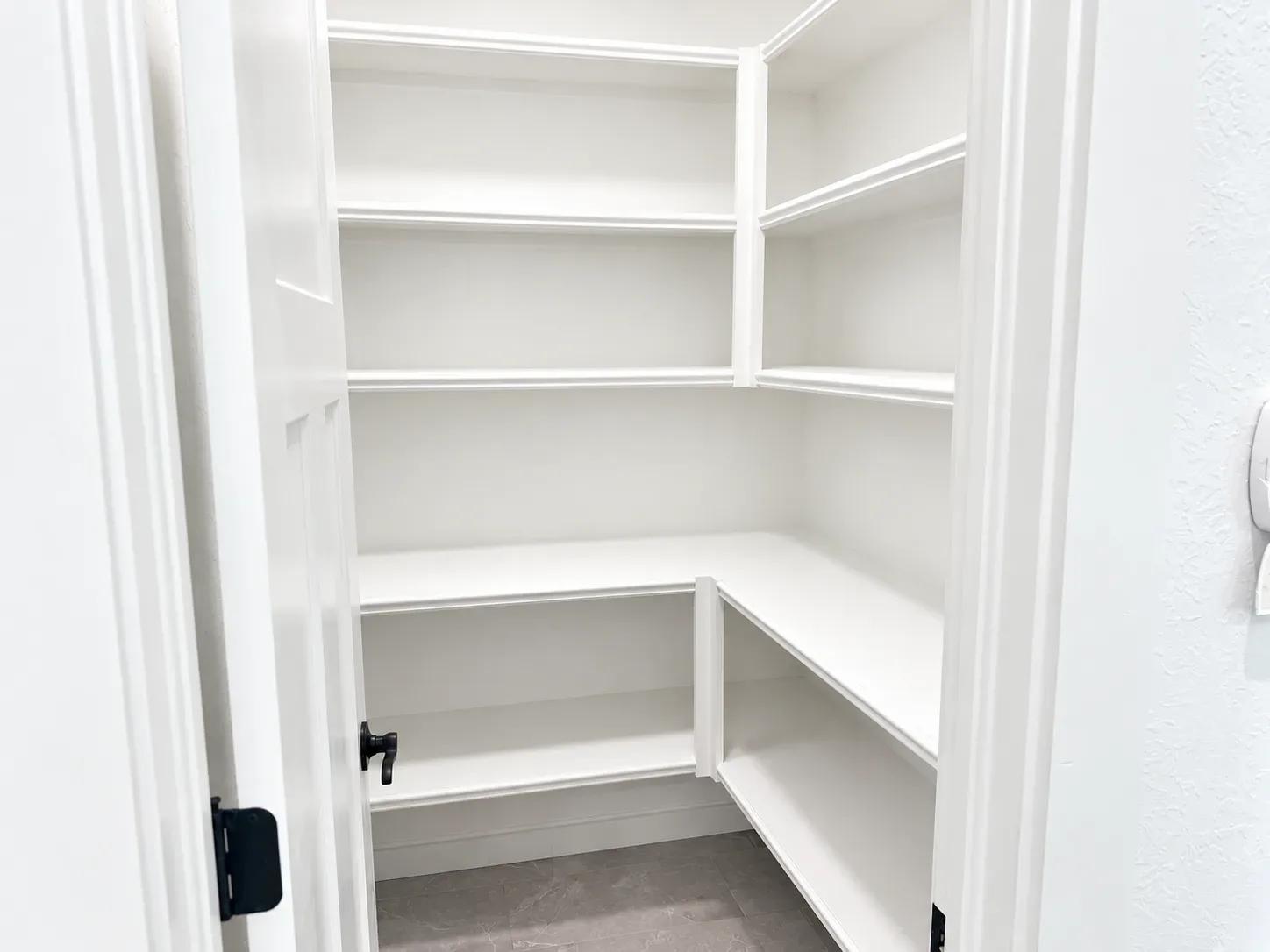 Walk-in pantry with clean white painted wood shelving