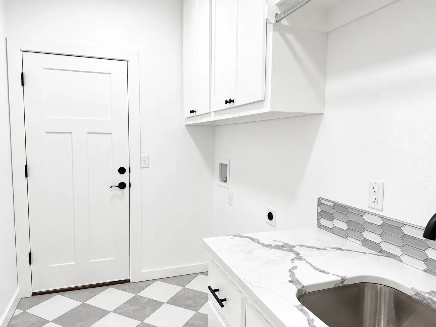 Laundry and mudroom with white cabinets, quartz countertop, hexagonal backsplash, and checkerboard floor tile