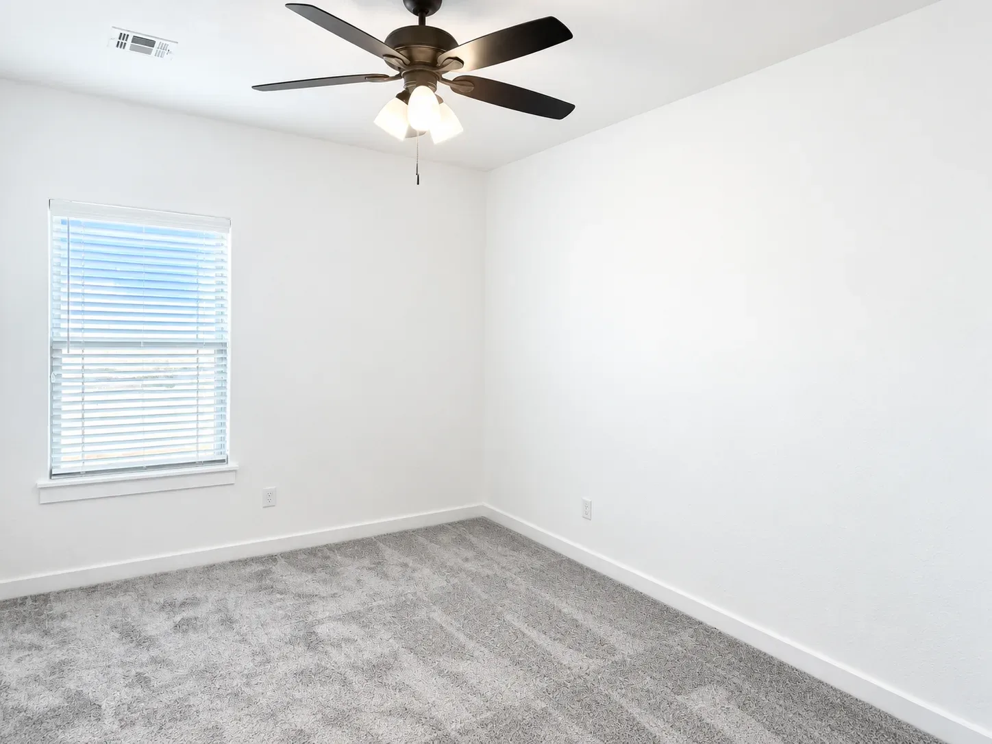 Bedroom with white walls, gray carpet, and window blinds