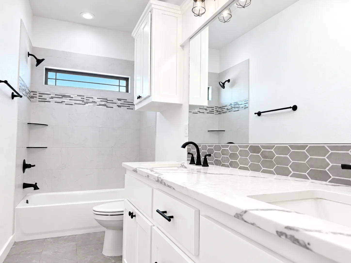 Modern renovated bathroom with white shaker vanity, marble-look countertop, hexagon tile backsplash, and matte black fixtures