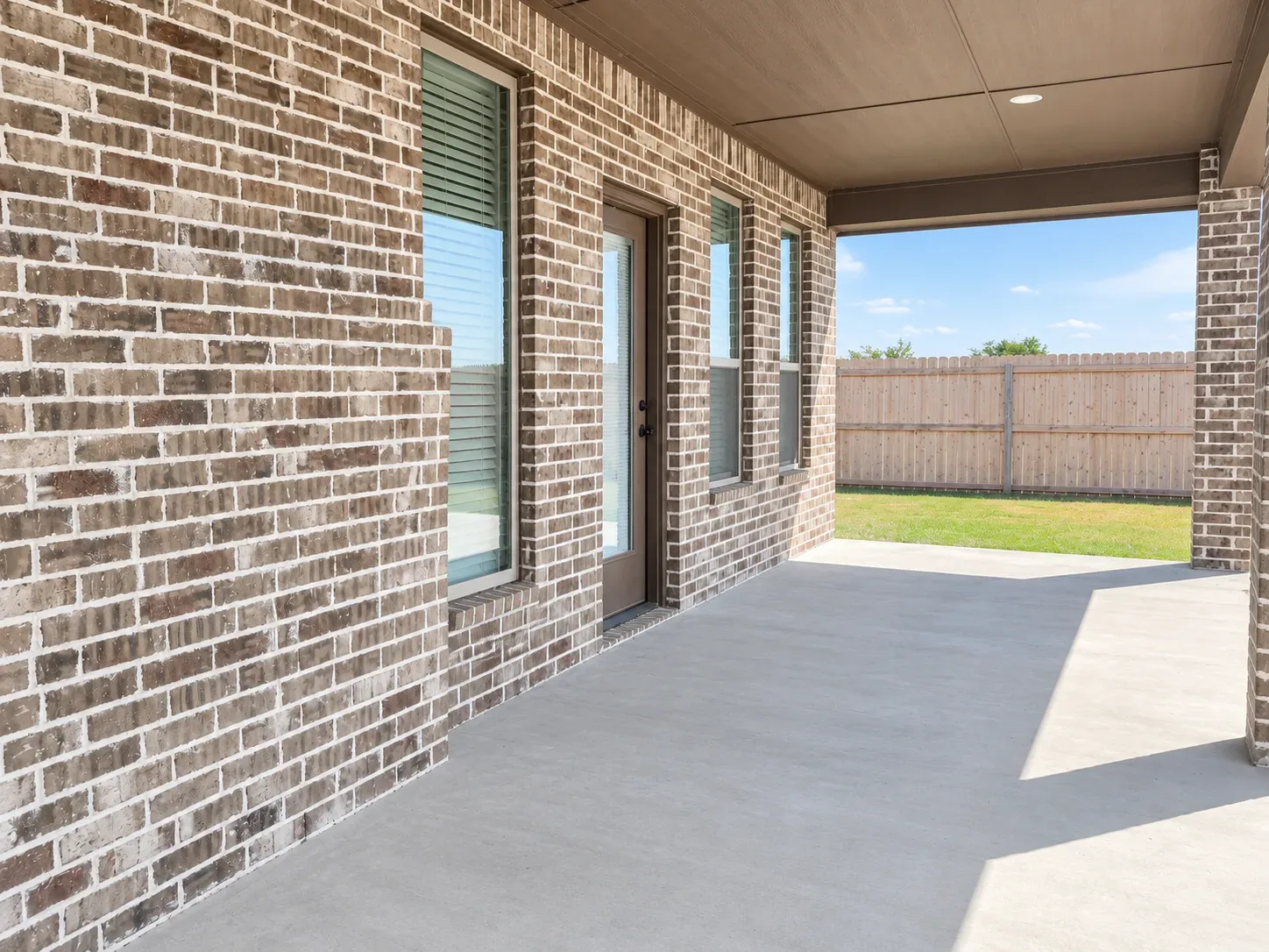 Covered patio off the rear of the home with recessed ceiling lighting and a view of the fenced lawn